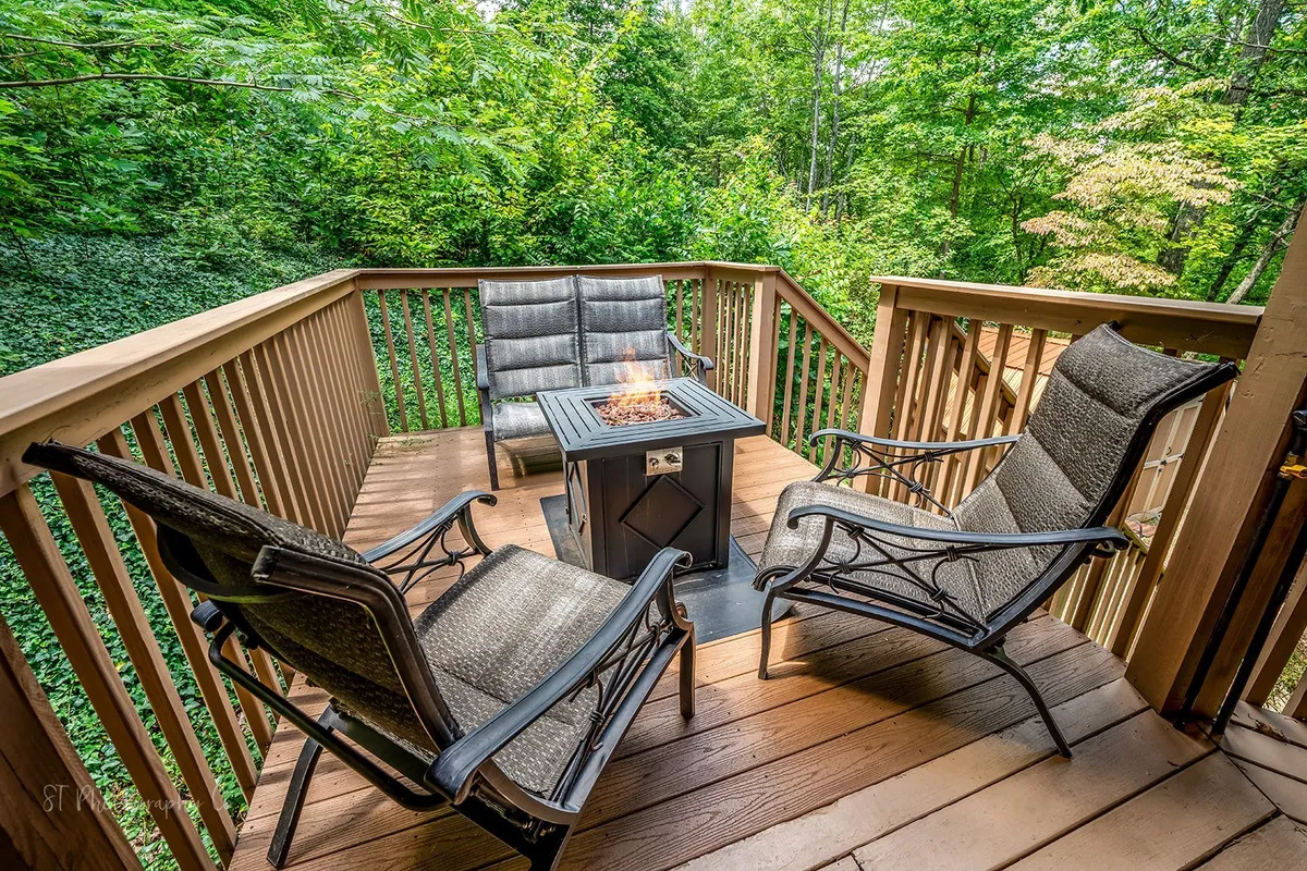 A cozy exterior shot featuring a fire pit with comfortable seating encircled by greenery. The atmosphere is peaceful and welcoming, ideal for evening gatherings, roasting marshmallows, and enjoying the serenity of the woods.