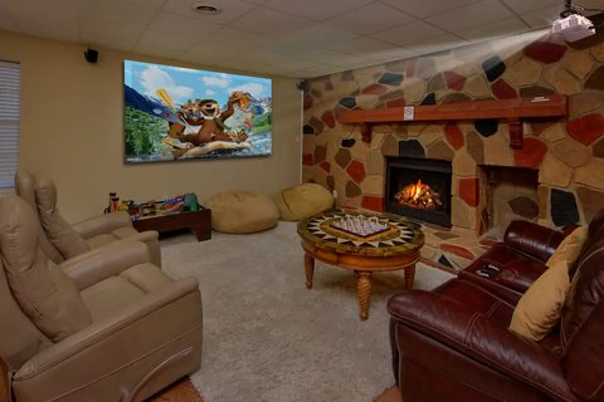 A cozy theater nook with a large television displaying animated characters, a fireplace, inviting bean bag chairs, and a central coffee table. The setting is playful and comfortable—perfect for movie nights or gaming marathons.