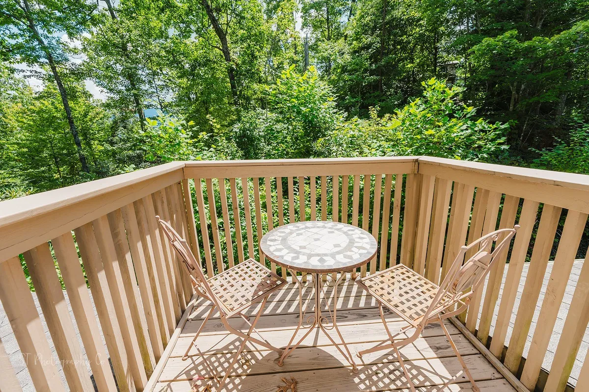 A tranquil outdoor nook with a small round table and two chairs set amidst lush greenery. The setting feels private and serene, inviting guests to enjoy a quiet morning coffee or read a book while immersed in nature.